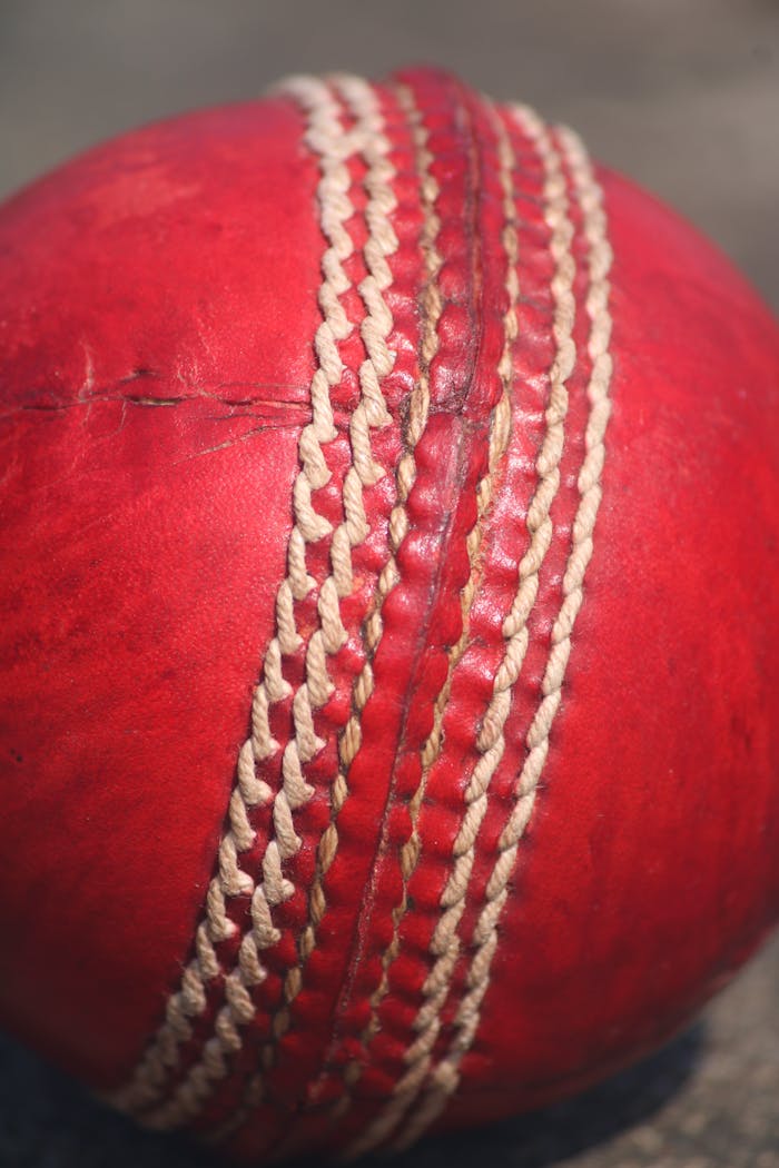 Home Detailed close-up of a red leather cricket ball showing stitches and texture.