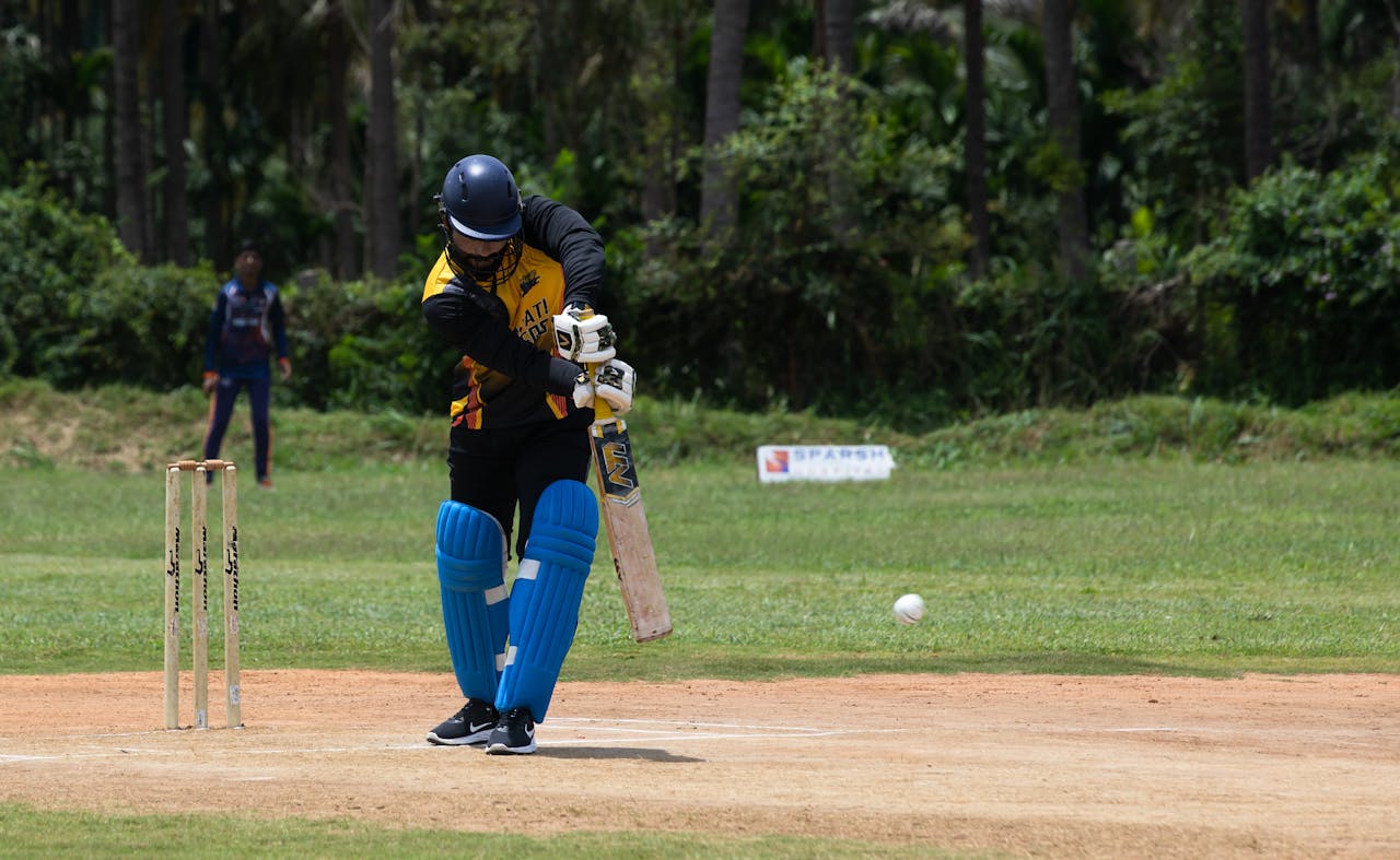 Home Cricketer making a powerful shot during a day game outdoors.
