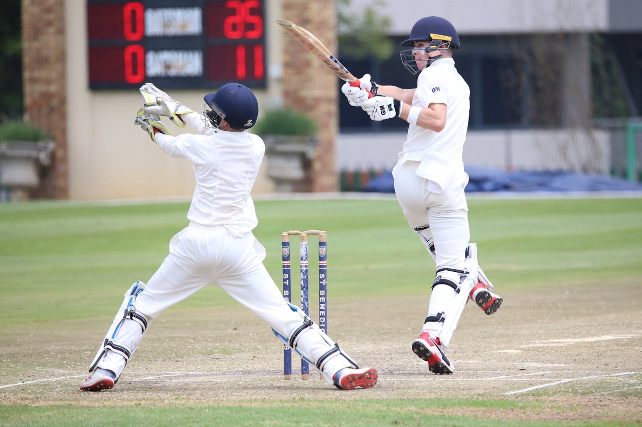 Pro Cricket Kit Dynamic cricket scene with batsman playing a shot and wicketkeeper in action.